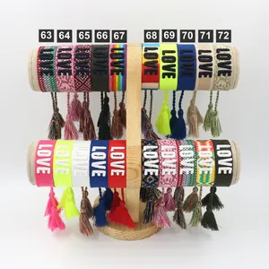 Detailed display of embroidered LOVE tassel friendship bracelets on a wooden stand