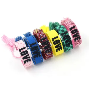 Detailed view of bohemian woven friendship bracelets with LOVE embroidery and colorful tassels