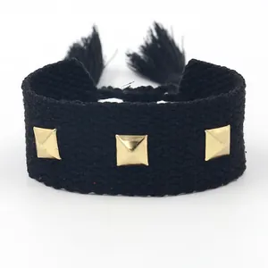 Bracelet tressé noir réglable avec clous carrés dorés et détails de pompons