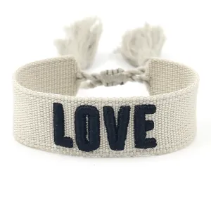 Close-up of 3D embroidered LOVE lettering and woven fringe details on friendship bracelet