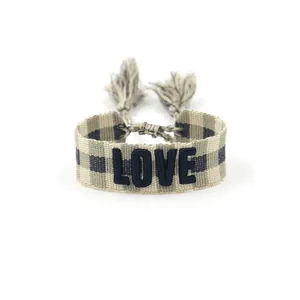 Close-up of woven friendship bracelet with LOVE embroidery and tassel detail