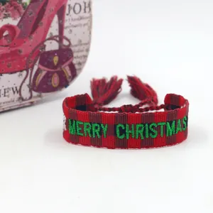 Macro shot of embroidered MERRY CHRISTMAS lettering on red checkered woven bracelet