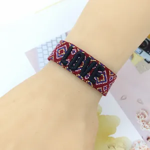 Detail shot of the red woven friendship bracelet with LOVE 3D embroidery and tassels