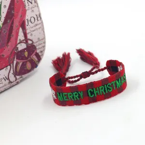 Close-up of red and black checkered woven bracelet with green Merry Christmas embroidery