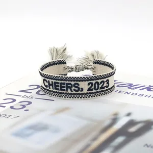 Adjustable woven friendship bracelet with CHEERS 2023 embroidery and tassel details