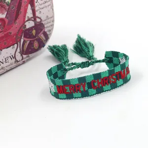 Detail of green plaid Merry Christmas woven bracelet with adjustable tassels and snowflakes