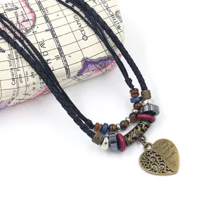 Détail macro du collier bohème en cuir avec pendentif cœur et perles en bronze