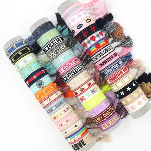 Macro shot of colorful embroidered cotton woven bracelets with tassels and motivational text