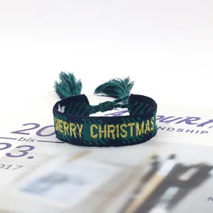Detail of woven friendship bracelet with Merry Christmas embroidery and tassel ties