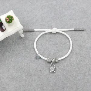 Détail d'un bracelet tressé blanc avec pendentif serrure argentée et fermoir magnétique