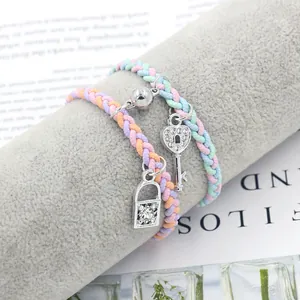 Close-up of magnetic heart lock and key charms on colorful braided friendship bracelets
