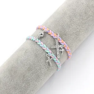 Détail de bracelets tissés avec boules magnétiques et pendentifs croix en strass colorés