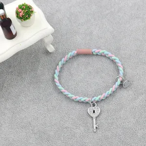 Close-up of pastel woven friendship bracelet with heart key charm and magnetic clasp