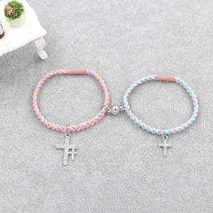 Détail de bracelets en corde tressée magnétique avec pendentifs croix et fermoir cœur