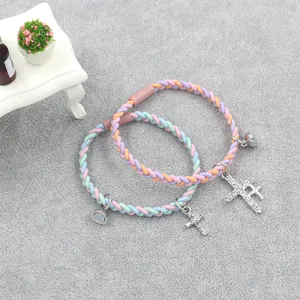 Gros plan de bracelets magnétiques pour couples avec croix en strass et cordes tressées