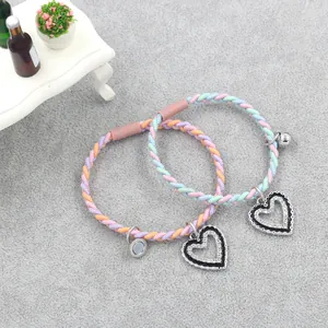 Close-up of woven couple bracelets with crystal heart pendants and magnetic clasp