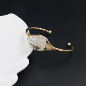 Macro-opname van handgemaakte gouddraad open armband met ruwe heldere kwarts