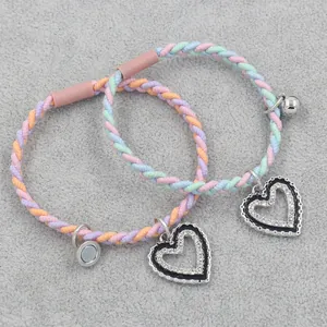 Handwoven friendship bracelets with magnetic heart charms and small bells in pastel colors