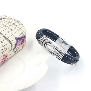Close-up of woven black leather bracelet with white stitching and antique silver knot charm