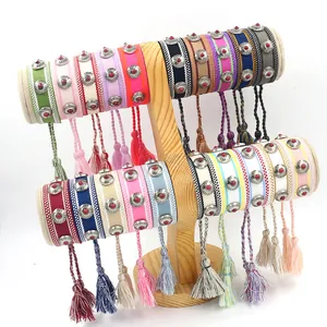 Bohemian hand-woven friendship bracelets with metal studs and tassel charms on wood stand