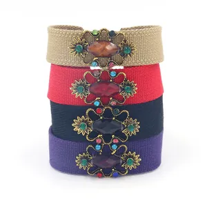 Detalle de pulseras de tela bohemia con flores de metal vintage y gemas de colores