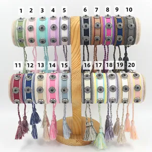 Primer plano de veinte pulseras tejidas con borlas y remaches metálicos de girasol