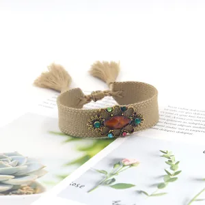 Detalle de pulsera tejida bohemia con borlas, piedra de ámbar y cristales de colores