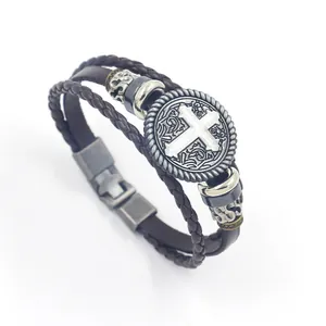 Detail view of multi-layer leather bracelet with cross emblem and vintage buckle