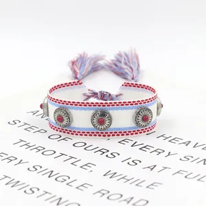 Detail of woven bohemian friendship bracelet with metal studs and tassels on card