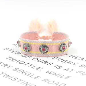 Detail of bohemian woven bracelet with metal studs, pink fringe and adjustable tie