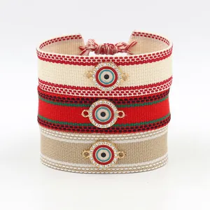 Three woven Evil Eye bracelets with rhinestone accents and tassels on a white background