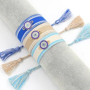 Detailed view of three braided Evil Eye friendship bracelets with tassels and rhinestones