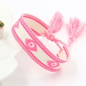 Detailopname van roze en witte geweven Evil Eye armband met kwastjes en verstelbaar koord