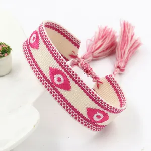 Detailopname van handgeweven Evil Eye-armband met roze borduursels en lange kwastjes
