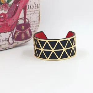 Detail of gold hollow cuff bracelet with black leather insert and vibrant red inner lining