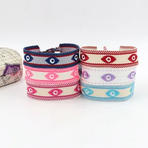 Gedetailleerd beeld van kleurrijke handgeweven Evil Eye armbanden met borduurwerk en kwastjes