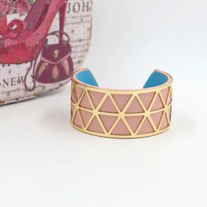 Macro detail of gold metal cutout bangle with pink leather and blue interior
