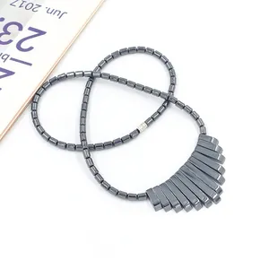 Donkergrijze hematiet kralenketting met een geometrische waaiervormige hanger op witte basis