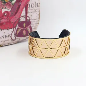 Detail of golden geometric cutout cuff bracelet with rose gold filling and matte black interior