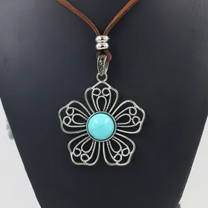 Detailed close-up of Bohemian alloy flower pendant with turquoise inlay on black mannequin