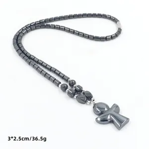 Detail van donkergrijze hematiet kralenketting met abstracte kruishanger en metallic glans
