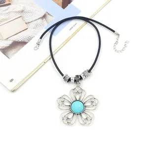 Detailed view of bohemian floral pendant with turquoise stone on black cord necklace