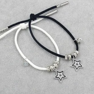 Detail van verstelbare koppelarmbanden met zwart en wit geweven touw en sterhangers
