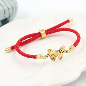 Bracciale a corda intrecciata rossa con ciondolo a farfalla dorata su vassoio in ceramica