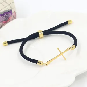 Adjustable black woven bracelet featuring a polished gold stainless steel cross charm