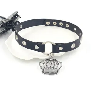Choker punk en cuir noir avec pendentif couronne et œillets sur un plateau blanc élégant