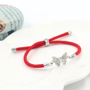 Détail du bracelet en corde rouge tressée avec breloque papillon et nœud coulissant