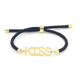 Detail of black woven rope bracelet with gold 'KISS' charm and adjustable sliding knot