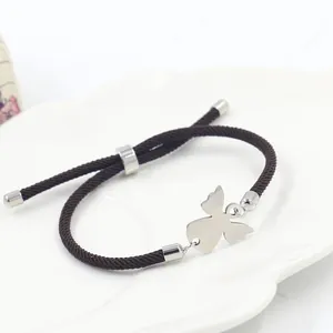 Détail d'un bracelet d'amitié marron tressé avec ange en argent sur une assiette blanche