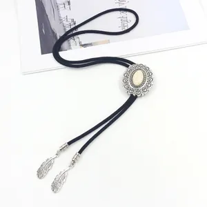 Detail of western bolo tie featuring white stone inlay and silver feather pendants